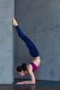 Slim young woman doing forearm stand or Peacock yoga pose against the wall