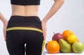 Slim young woman measuring her buttocks with a tape measure. In focus fruits for weight loss - apple, orange and pear. Royalty Free Stock Photo