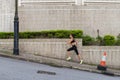 Slim young woman running uphill on sidewalk of city street. Female athlete training outside Royalty Free Stock Photo