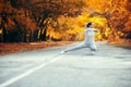 Slim young woman in sportswear exercises and stretches on asphalt road, girl engaged in sport outdoors on background of Royalty Free Stock Photo