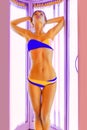 Slim young woman standing in solarium getting sun tan Royalty Free Stock Photo