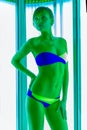 Slim young woman standing in solarium getting sun tan Royalty Free Stock Photo