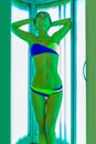 Slim young woman standing in solarium getting sun tan Royalty Free Stock Photo