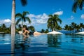 Slim young woman in swimsuit relaxing on edge tropical infinity pool in hawaii. Palms around and crystal clean water Royalty Free Stock Photo