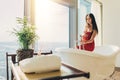Slim young woman in towel sitting on bathtub in luxurious bathroom