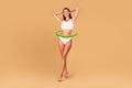 Slim young woman in underwear posing on beige studio background, green circle arrows around waist, collage