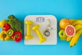Flat lay composition of scales, dumbbells and tape measure, plate with fruits and vegetables on blue background Royalty Free Stock Photo