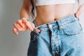 Woman holds jeans in hand, shows a thin waist Slim female body in large jeans Royalty Free Stock Photo