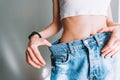 Woman holds jeans in hand, shows a thin waist Slim female body in large jeans Royalty Free Stock Photo