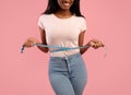 Slimming and dieting concept. Unrecognizable black woman measuring her waist during weight loss over pink background Royalty Free Stock Photo