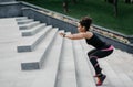 Slimming workout. Fitness african american girl with wireless headphones and fitness tracker jumping on stairs Royalty Free Stock Photo