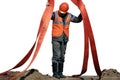 A slinger in a helmet and overalls unloads the load using slings. A man at work in production.