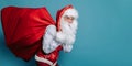 Slinking santa claus carrying a full bag of gifts while looking at camera. New Year concept Royalty Free Stock Photo