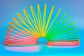 Slinky, plastic toy with colors of the rainbow, colorful children`s spring on a blue background Royalty Free Stock Photo