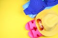 Slippers, swimsuit bikini, towel, hat and sunglasses on a pastel yellow background. Travel, sea, vacation, holiday. Royalty Free Stock Photo