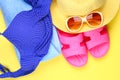 Slippers, swimsuit bikini, towel, hat and sunglasses on a pastel yellow background. Travel, sea, vacation, holiday. Royalty Free Stock Photo