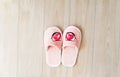 Slippers for women, children, soft, pink with a heart sticker on the wooden floor, close-up.