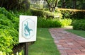 Slippery sign beside walkway in garden in morning Royalty Free Stock Photo