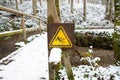 Slippery warning sign in the forest, wooden bridge covered with snow, winter season, beware of danger, outdoor