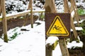 Slippery warning sign in the forest, wooden bridge covered with snow, winter season, beware of danger, outdoor