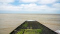 Slipway with slippery moss in the ocean. Cloudy sky.