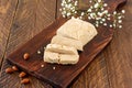 Slised sunfower halva dessert on a serving wooden board on a table. Sweet oriental dessert from nuts and seeds