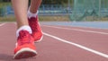 Legs in red snikers of a young woman athlete who training running at the city athletics stadium during a day training in
