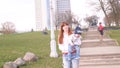 Young beautiful woman carries on hands her crying baby boy in the city park on the granite stairs background on sunny