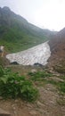 On the slope of a high mountain with a green slope and a top in clouds and fog. Sports and tourist base in the mountains. Krasnaya