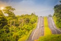 Slope highway with sunshine and green traffic island. Four lane Royalty Free Stock Photo