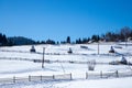 Slope of a hill with wooden fences and haystacks covered with snow Royalty Free Stock Photo