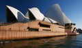 Playful dancing of white shells of curved and pointy roofs on large pink waterfront podium at Sydney Opera House Australia