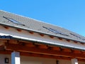 Sloped gray metal tile residential roof with skylights under blue sky