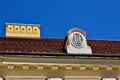 sloped red clay tile residential roof with decorative dormer. oval wood window. yellow stucco ornate chimney.