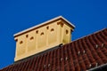 sloped red clay tile residential roof with decorative yellow stucco chimney. concrete capping