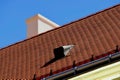 Sloped red clay tile roof. black zink plated roof dormer. white stucco chimney. blue sky