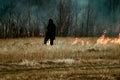 sloping field and a man sets fire to dry grass