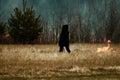 sloping field and a man sets fire to dry grass