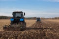 The sloping field. Two large blue traktor plow plowed land after harvesting the maize crop