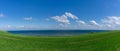 Sloping green grass farm field leading down to the shores of the North Sea at the Limfjord in northern Denmark Royalty Free Stock Photo