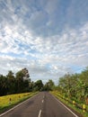 sloping road in the countryside of Tiyinggading village, Tabanan with yellow rice fields on the sides with white clouds