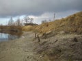 Sloping shore and water in the foreground, forest in background, autumn, tree shadows Royalty Free Stock Photo