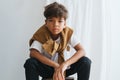 Slouching indian boy sitting on a low pedestal, looking at the camera