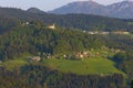 Slovenian countryside in spring with charming little village and small white church on a hill, surrounded by Julian Alps mountains Royalty Free Stock Photo