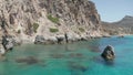 Slow Dolly Aerial in between rock fomations in Turquoise Blue Ocean Water on Greek Island Milos