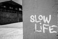 Slow Life sign written on concrete wall against view of old building and empty street Royalty Free Stock Photo