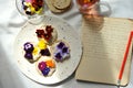 Slow living conceptual photography with edible flowers snacks and diary on a white table