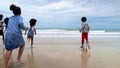 Slow motion, african-American children are holding hands running on the beach in the summer