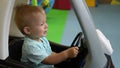 Slow motion. Child steers wheel in toy car. ChildrenÃ¢â¬â¢s play center. Boy drives toy car