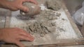 Slow motion of a craftsman pulverizing dry clay with a stone